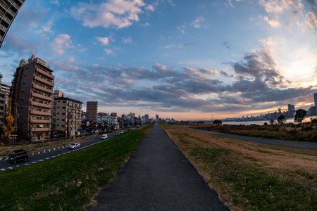 View of a path with buildings on the left and the riverside on the right during a sunny day (Umeda, Osaka, Japan) (fish-eye effect) (20221220-024)の写真素材