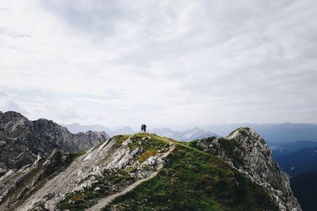 Silhouette of two people on a mountain peak in the Alpsの写真素材
