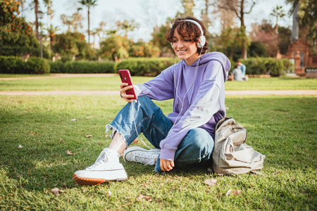 Young girl using headphones and mobile phone, listening to music and having fun in the park.の写真素材