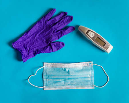 Medical face mask, thermometer and a glove on blue background.の写真素材