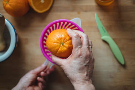 Woman putting an orange on a squeezer to make orange juice in the morning (view from above).の写真素材