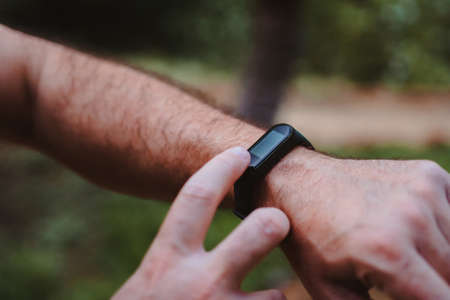 Close-up of a man touching his smart-band while he is taking a break from running.の写真素材