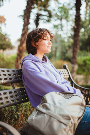 Girl sitting on a bench in a park. She is resting and relaxed.の写真素材
