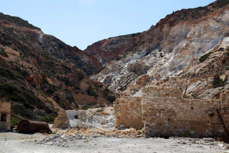 abandoned sulfur mine with a rusted and weathered silo next to the red cliffsの写真素材