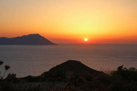 dramatic sunset on Greek island overlooking the seaの写真素材