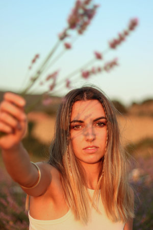 Portrait of beautiful young woman looking ahead holding lavender flowersの写真素材