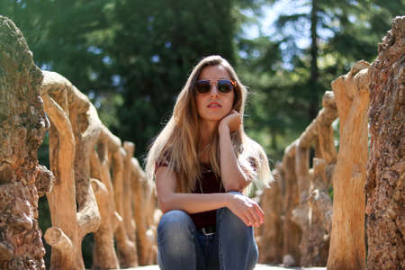 Young girl sitting casually on the path of a wooden branch bridgeの写真素材