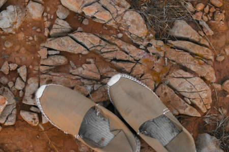 Textured background of sandals over stones and soil