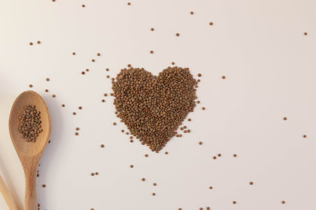 Heart made of raw lentils on a white background with kitchen utensilsの写真素材