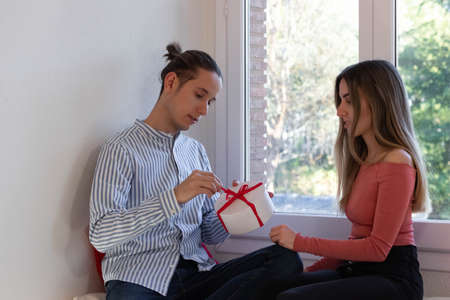 Young man opening valentines gift from his wife