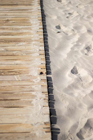 Wooden pathway leading to the beach surrounded by golden sand