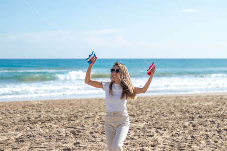 Portrait of happy, smiling young woman flying a kite on the beachの写真素材