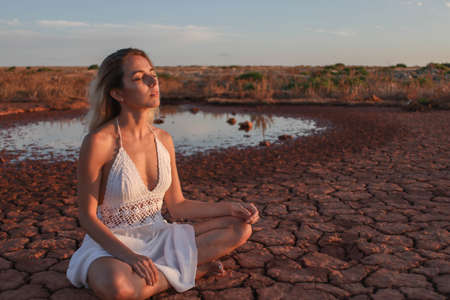 beautiful young girl meditating outdoors in the desertの写真素材