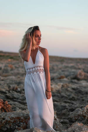 woman dressed in vintage clothing on desert rocks at sunsetの写真素材