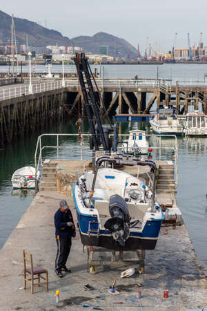 Man fixing fishing boat in port in townの写真素材