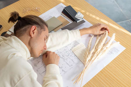 Young man sleeping on desk during work of architecture and interior design