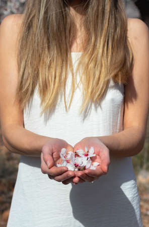Close up of blonde woman in white dress holding white flowers in her handsの写真素材