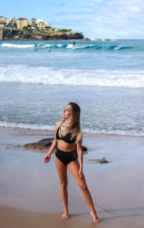 Young blonde woman with her eyes closed on Bondi Beach in Sydney with surfersの写真素材