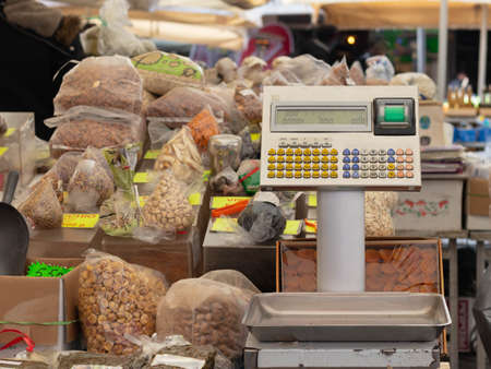 Weight scale in a street market sorrounded by a variety of products and nuts