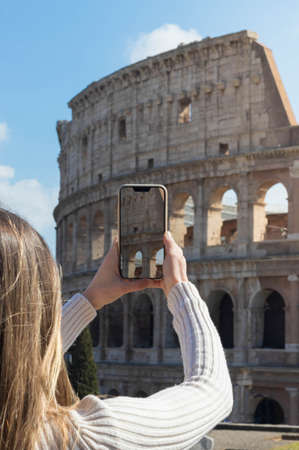 Woman taking picture of the colosseum in Rome with her smartphoneの写真素材