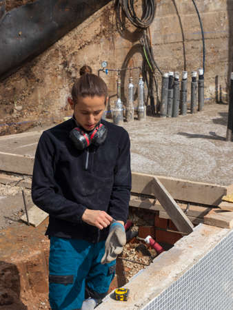 Young laborer putting on a work glove while working on a construction siteの写真素材
