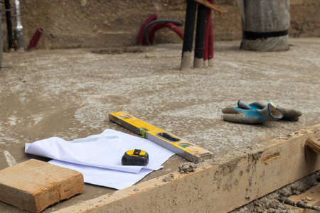 Construction objects and tools perched in concrete floor on construction site