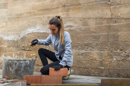 Woman bricklayer preparing laying bricks to build her own houseの写真素材