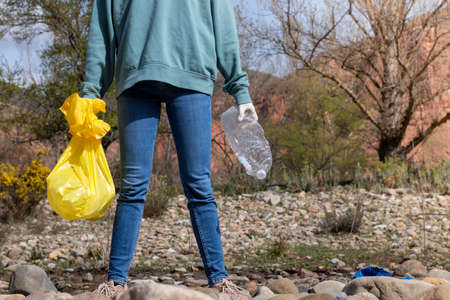 Decisive woman with her legs open facing the harsh reality of garbage in nature