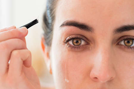 Portrait of yellow color eyes crying after plucking her eyebrowsの写真素材