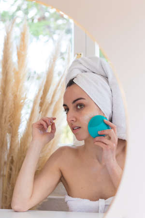 Woman cleaning skin with ultrasonic device during morning hygiene proceduresの写真素材