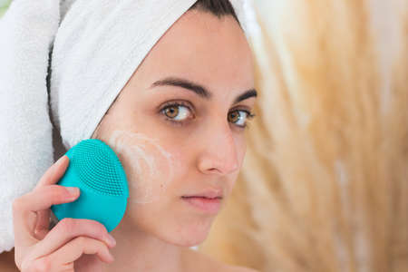 Close up portrait of woman washing her face with a silicone brush for cleansingの写真素材