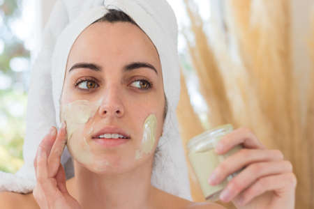 Portrait of beautiful woman putting cosmetic mask on her face to purify skinの写真素材