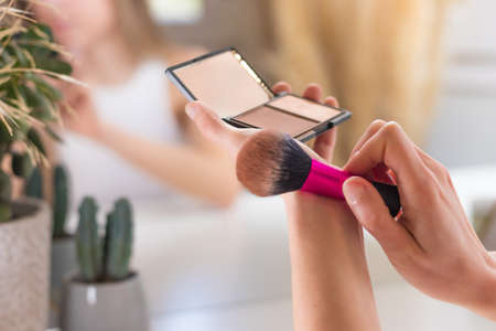 Close up view of make up bronzer and brush shaking the excess of loose powderの写真素材