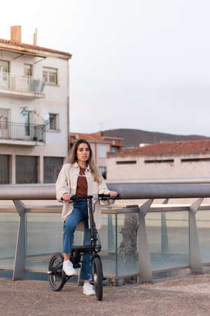 Woman looking at camera while riding an electric bike going home to a poor european town with copy spaceの写真素材