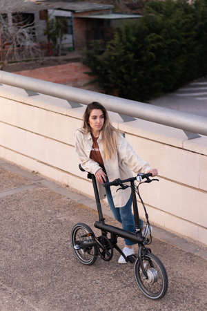 Top view of young woman leaning and holding an electric bicycle wich uses alternative energy to be energy efficientの写真素材