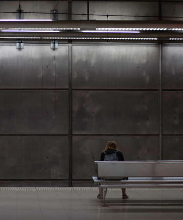 BILBAO, SPAIN-MAY, 5TH, 2022: Vertical view of backwards sitting woman wating for the underground to comeのeditorial素材