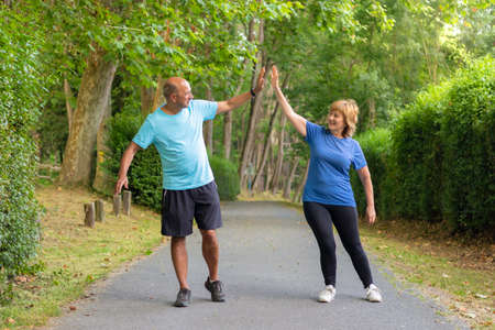 Man and woman giving five to each other after having finished an exercise well in an urban parkの写真素材