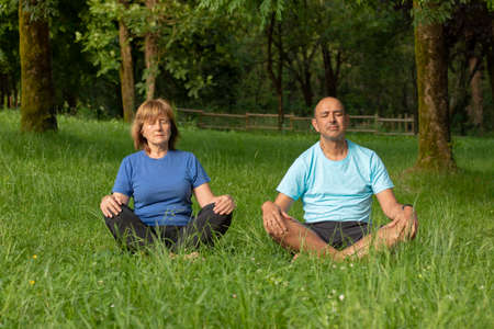 Two elder adults meditating in nature enviroment to breath clean air and have healthy lifestyleの写真素材