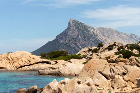 Beautiful sardinian sea shore landscape with granite rocks and Isola Cana in the background.