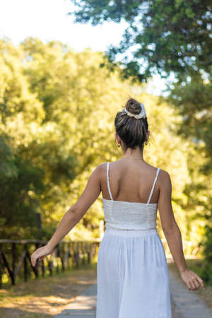 Vertical view of young brunette woman wearing a bun hairstyle on a boho outfit on a hot summer dayの写真素材
