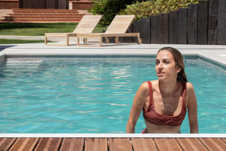 Front view of young happy woman smiling in the swimming pool while having fun and copy space around