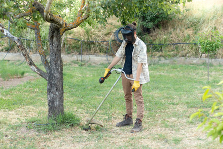 Farmer with farm equipment working in his garden and removing grasses from his meadow in summer