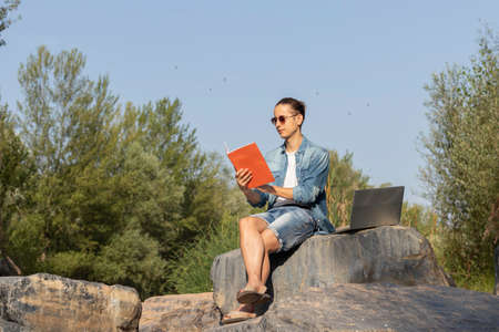 Low angle view of a young boy in a ponytail hanging out at the break from his remote work among the...