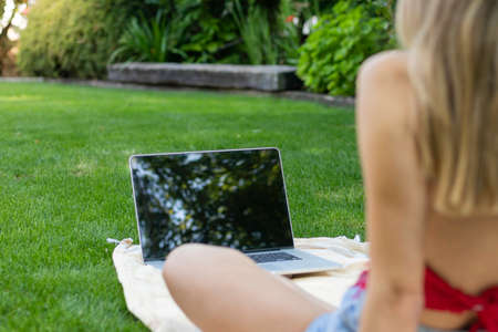 Selective focus of unrecognizable young woman using her laptop to be online while exploring the natural enviromentの写真素材