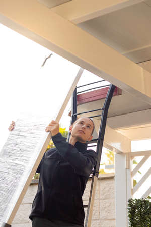 Low angle view of professional technician holding a solar panel to be installed for renewable energyの写真素材