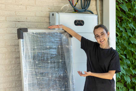 Young woman labourer showing and pointing the new solar panels to be install to get solar green eco energyの写真素材