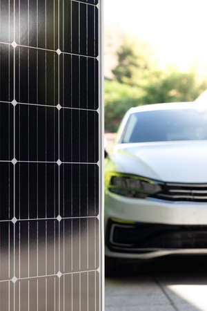 Vertical view of blurred modern white electric car powered with solar panels in focus as renewable energy conceptの写真素材