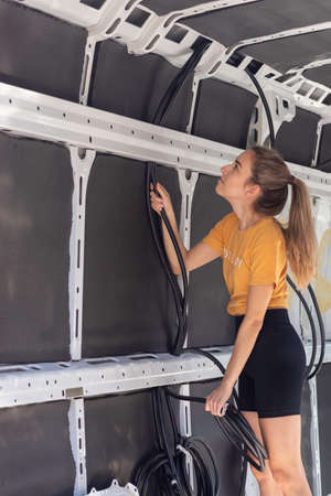 Young woman passing through the electrical wiring for the electricity instalation of the self built camper vanの写真素材