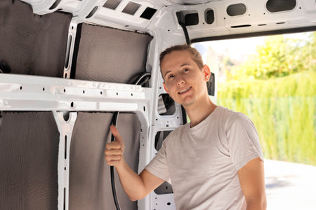 Young man looking to camera with thumbs up sign after making a great job isolating the camper vanの写真素材