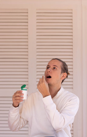 Vertical view of young hipster man taking a medical pill as medicine for hair growingの写真素材